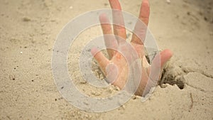 Male hand sinking in puddle of quicksand, dangerous travels in desert, closeup