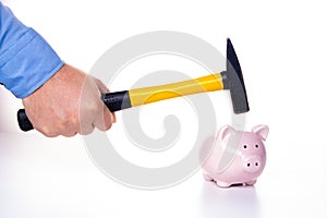 Male hand smashes a pink pig piggy bank with a hammer on a white background. The concept of savings and savings