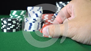 Male hand sorting through a stack of red poker chips. Chips fall on each other back to the turret
