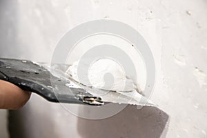 Male hand with a spatula putty wall. . Align the wall. White wall. Putty on the wall