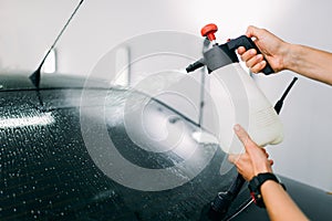 Male hand with spray, car window tint installation