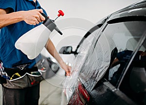 Male hand with spray, car window tint installation