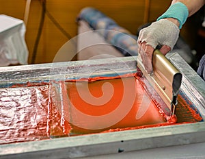 male hand with a squeegee. serigraphy production selective focus photo. printing images on clothes by silk screen method in a