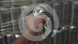 Male hand squeezes an aluminum can on the background of beer tanks. Inside the brewery.