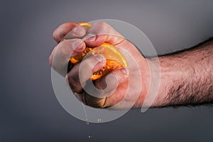 Male hand squeezing orange.