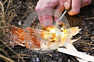 Male hand starts fire with magnesium fire steel, fire striker photo