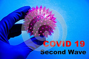 A male hand in sterile blue medical gloves holds in his hand, with his fingers a virus, a molecule, the core of a coronavirus on a