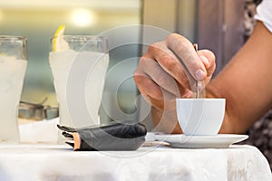 Male hand stirring a espresso coffee cup on a table outdoors, Italy