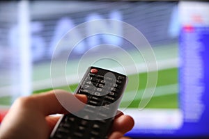 Male hand switching the channels to a soccer match with a remote control