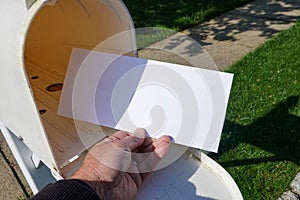 A male hand taking a blank white envelope out of a mailbox