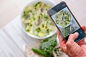 Male hand taking photo alternative vegetable pasta by mobile phone. Zoodle