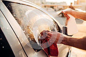 Male hand with tool for washing windows, car wash