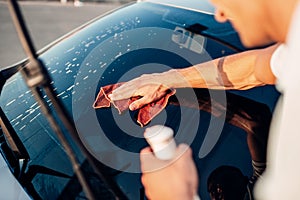 Male hand with tool for washing windows, car wash