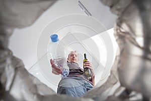 Male hand trowing a plastic bottle into a garbage bin