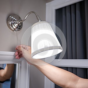 Male hand turn off the light on wall lamp