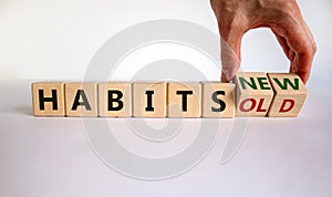 Male hand turning a cube and changes the expression `old habits` to `new habits`. Beautiful white table, white background. Con