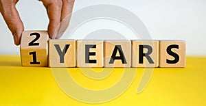 Male hand turns cubes and changes the expression `1 year` to `2 years` or vice versa. Beautiful yellow table, white background