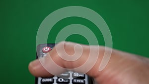 Male hand with TV remote pressing button turn the tv on or off on green screen.