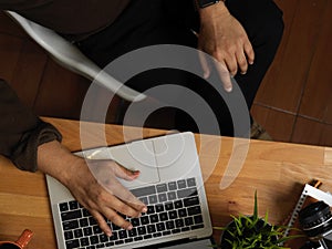 Male hand typing on laptop keyboard on wooden worktable in office room