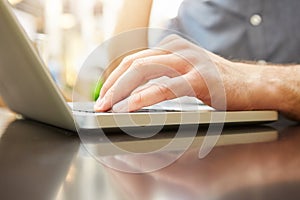 Male hand typing on laptop at outside cafe