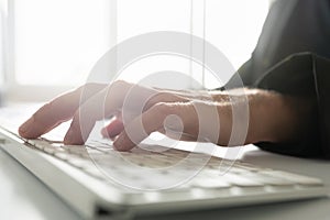 Male hand typing on white computer keyboard