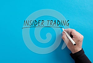 Male hand underlines the word insider trading on blue background