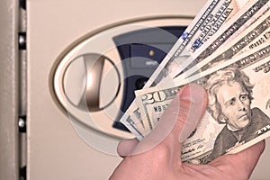Male hand with US dollars on the background of the safe with the door open. The concept of saving money, service in a hotel or