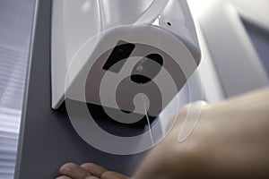 Male hand using automatic alcohol dispenser for cleaning hands in the office or hospital to sanitize virus and bacteria -