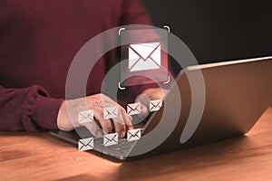 Male hand using a computer laptop typing on keyboard and surfing the internet on office table with email icon