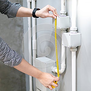 Male hand using tape measure on electrical conduit