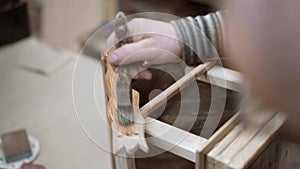 Male hand varnishing handmade new furniture in woodcraft studio