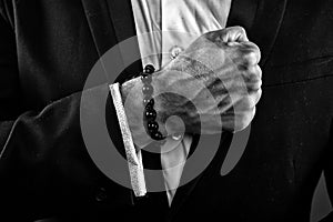 Male hand with veiny skin. Man wearing white shirt and black jacket. Businessman clenching fist. Prayer beards on wrist