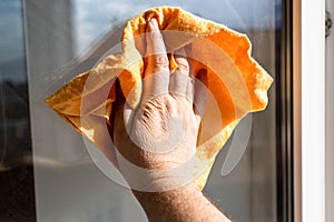 male hand wipes surface of window glass with rag