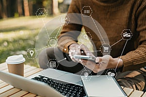 Male hand working with smartphone and laptop.