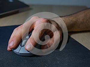 Male hand works with wireless mouse on table