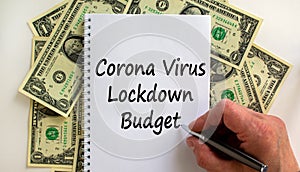 Male hand writing `corona virus lockdown budget` on white note, on white background. Dollar bills