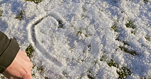 Male hand writing heart in snow