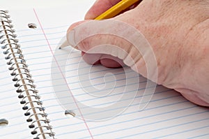 A male hand writing on lined notepaper