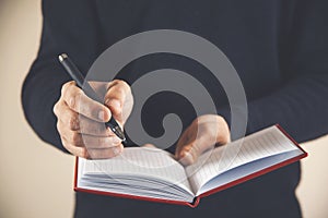 Male hand writing in notebook with pen