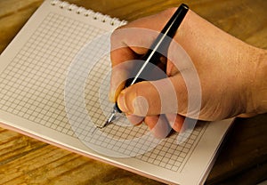 Male hand writing using fountain pen on a notebook