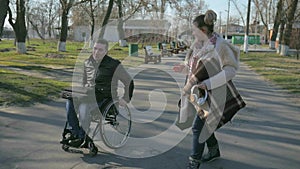 Male handicapped and girl walk along embankment, cripple person