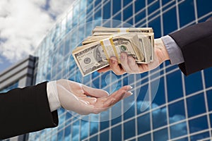 Male Handing Stack of Cash to Woman with Corporate Building