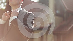 Male hands adjusting bow tie closeup. Young man touching puts and adjusts touching funky dots bow tie on white shirt