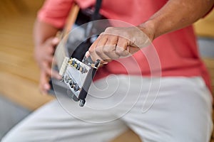 Male hands adjusting guitar strings outdoors