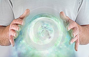 Male with hands around a green heart chakra orb of energy photo