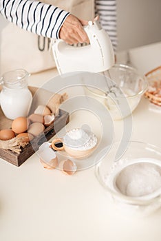 Male hands beating egg whites cream with mixer in the bowl