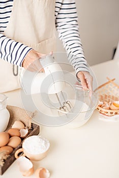 Male hands beating egg whites cream with mixer in the bowl