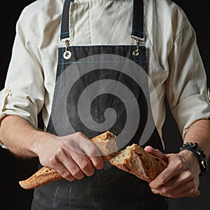 Male hands break the baguette