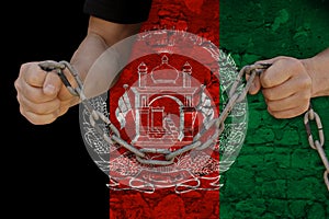 Male hands break the iron chain, a symbol of bondage,protest against the background of the Afghanistan national flag on old stone