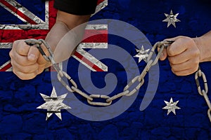 Male hands break the iron chain, a symbol of bondage,protest against the background of national flag of Australia on old wall,